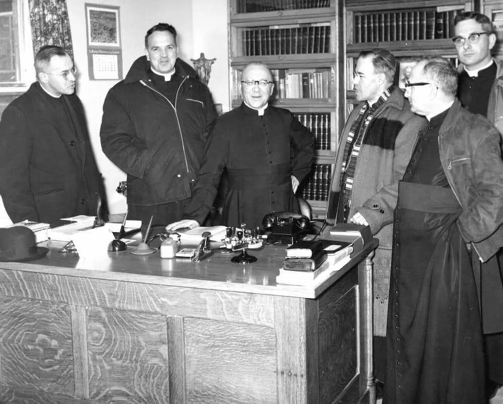 Mgr Couturier et les membres de la visite réunis dans un bureau du chantier